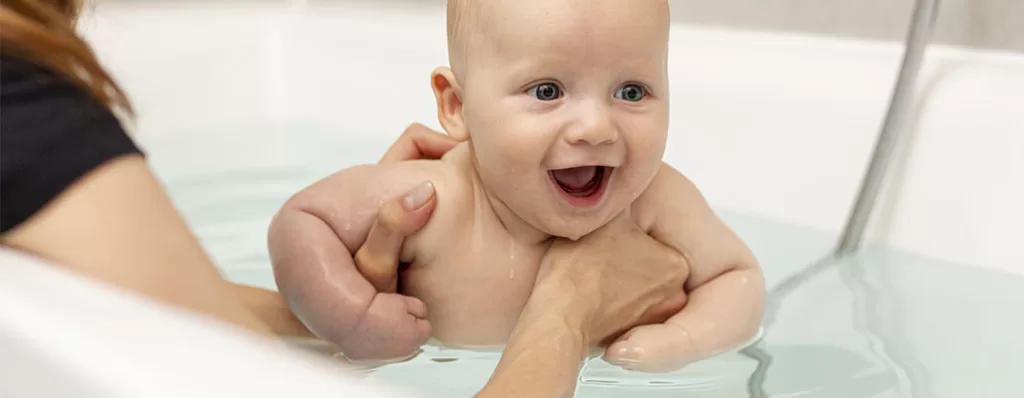 Bebê tomando banho na banheria. 